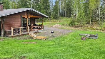 Una baita di legno con veranda, barbecue e una piccola terrazza.