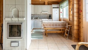 Een gezellig keuken in landhuisstijl, met een open haard, houten kastjes en een eethoek met een bank.