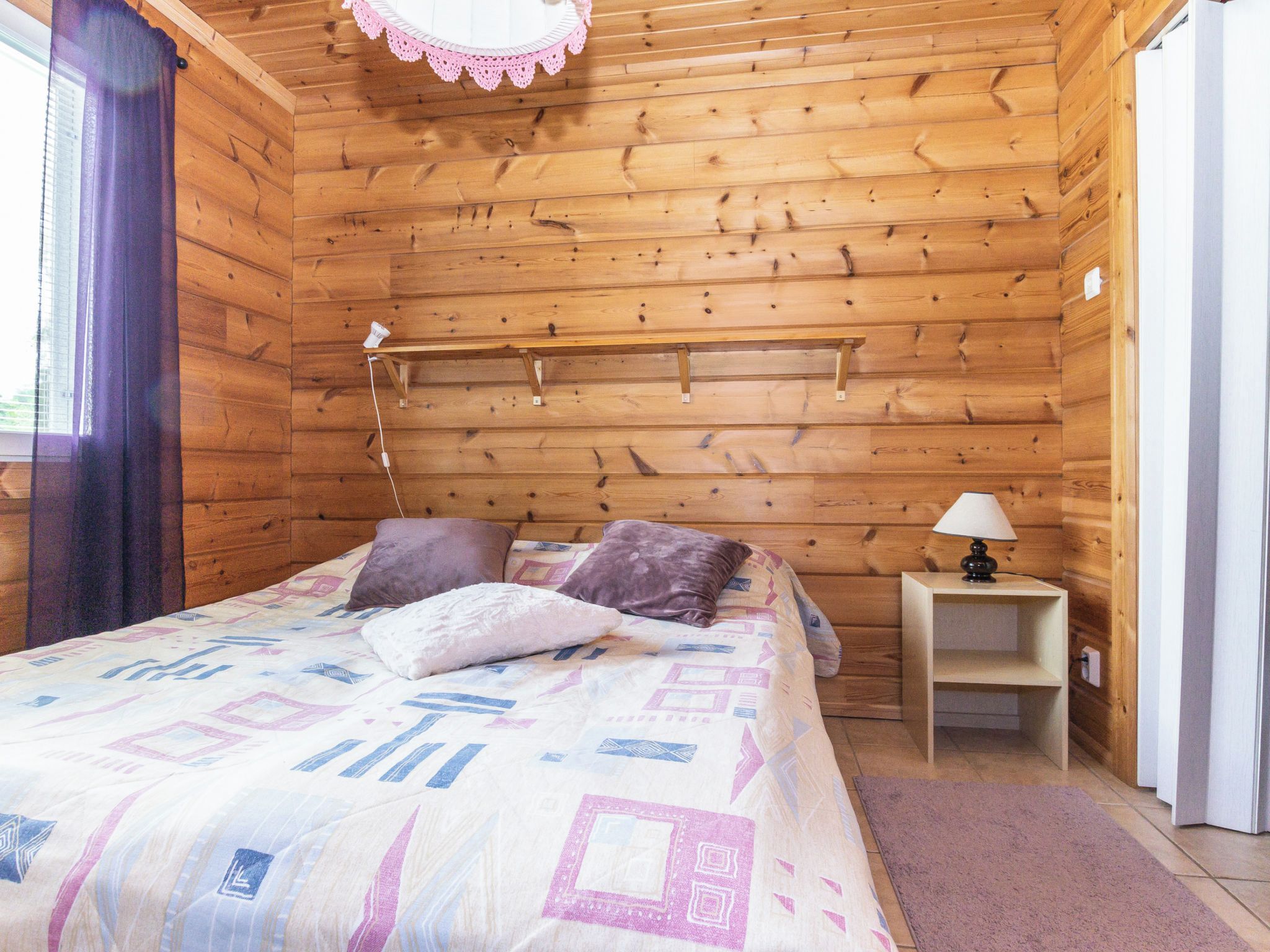 Une pièce en bois avec un lit, des oreillers, une table de chevet et une lampe.