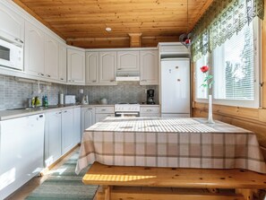 Una cucina con mobili bianchi, un forno a microonde, una macchina da caffè e un frigorifero.