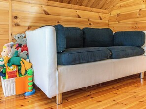 Un interno in legno con un divano e un cesto di giocattoli.