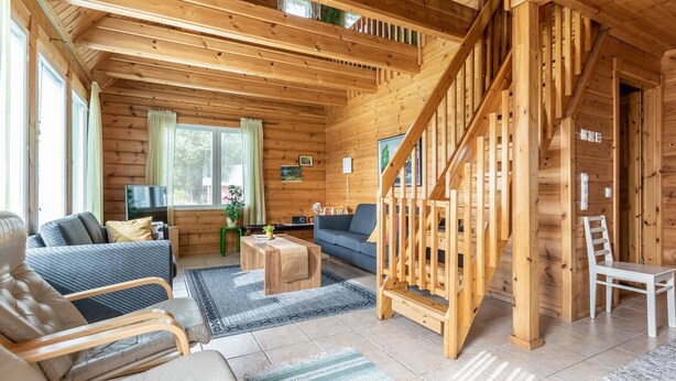 Een gezellig houten blokhut interieur met een woonkamer, bank, salontafel en een trap.