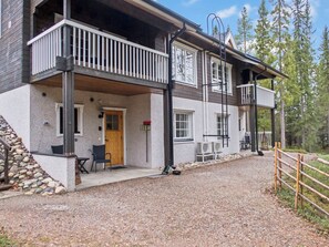 A two-story building with a balcony, a gravel driveway, and a wooden fence. - Weekend duo by Interhome (Sotkamo)