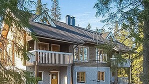A two-story wooden house with a balcony, surrounded by trees. - Weekend duo by Interhome (Sotkamo)
