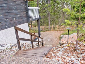 A wooden staircase leading to a building with a white railing, surrounded by gravel and rocks. - Weekend duo by Interhome (Sotkamo)