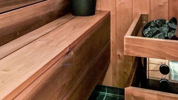 A wooden sauna with benches, a black bucket, and a dish rack. - Weekend duo by Interhome (Sotkamo)