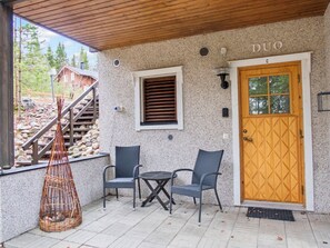 A covered outdoor seating area with a wooden door labeled 'DUO' and a stone wall.