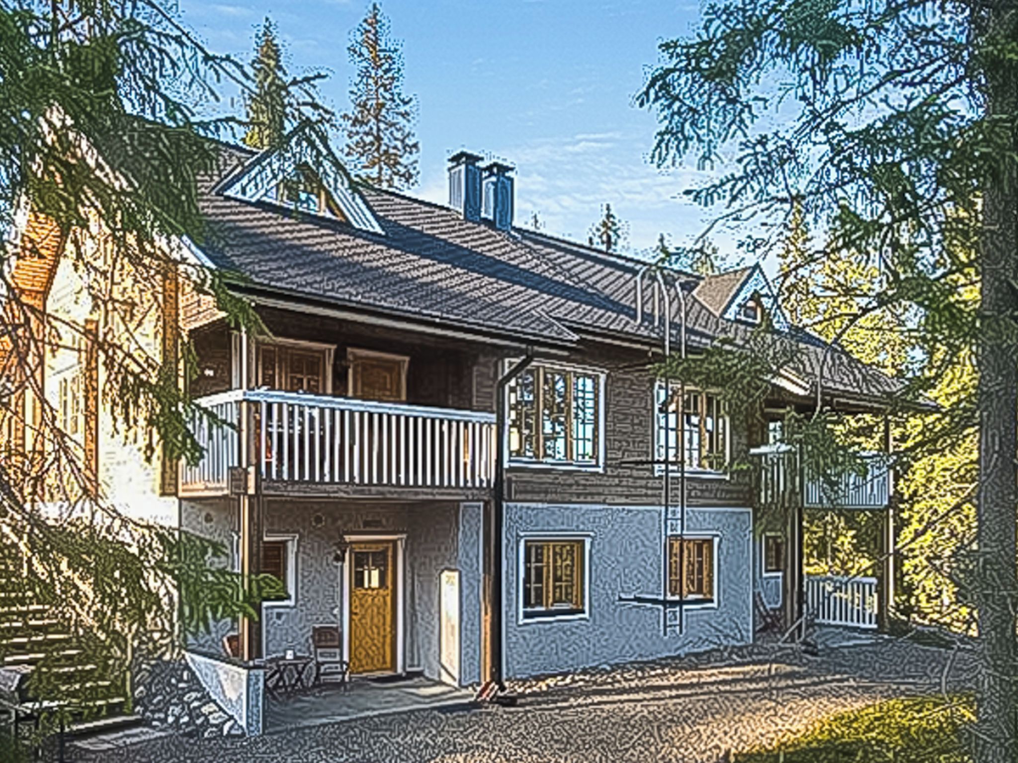 Een tweelaags huis met een balkon, een veranda en een schoorsteen.