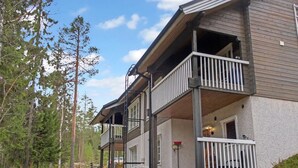 A two-story building with a balcony, a covered outdoor seating area, and a staircase leading to the entrance. - Weekend duo by Interhome (Sotkamo)