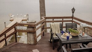 Une terrasse en bois avec une table dressée pour le repas, donnant sur un lac paisible.