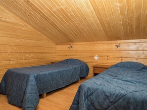 Una cabaña con dos camas individuales, paredes de madera y techo inclinado.