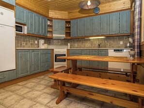 Une cuisine avec des armoires bleues, un plafond en bois, une cuisinière encastrée et un banc en bois.