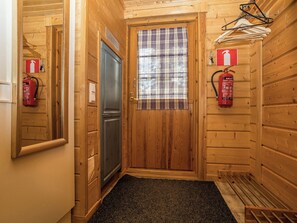 Un couloir intérieur en bois, avec une porte, un extincteur et un panneau d’information sur la sécurité incendie.