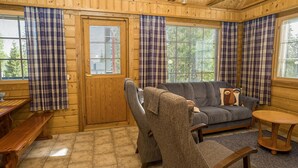 A cozy cabin interior with a wooden interior, a sofa, a chair, a small table, and a bench.