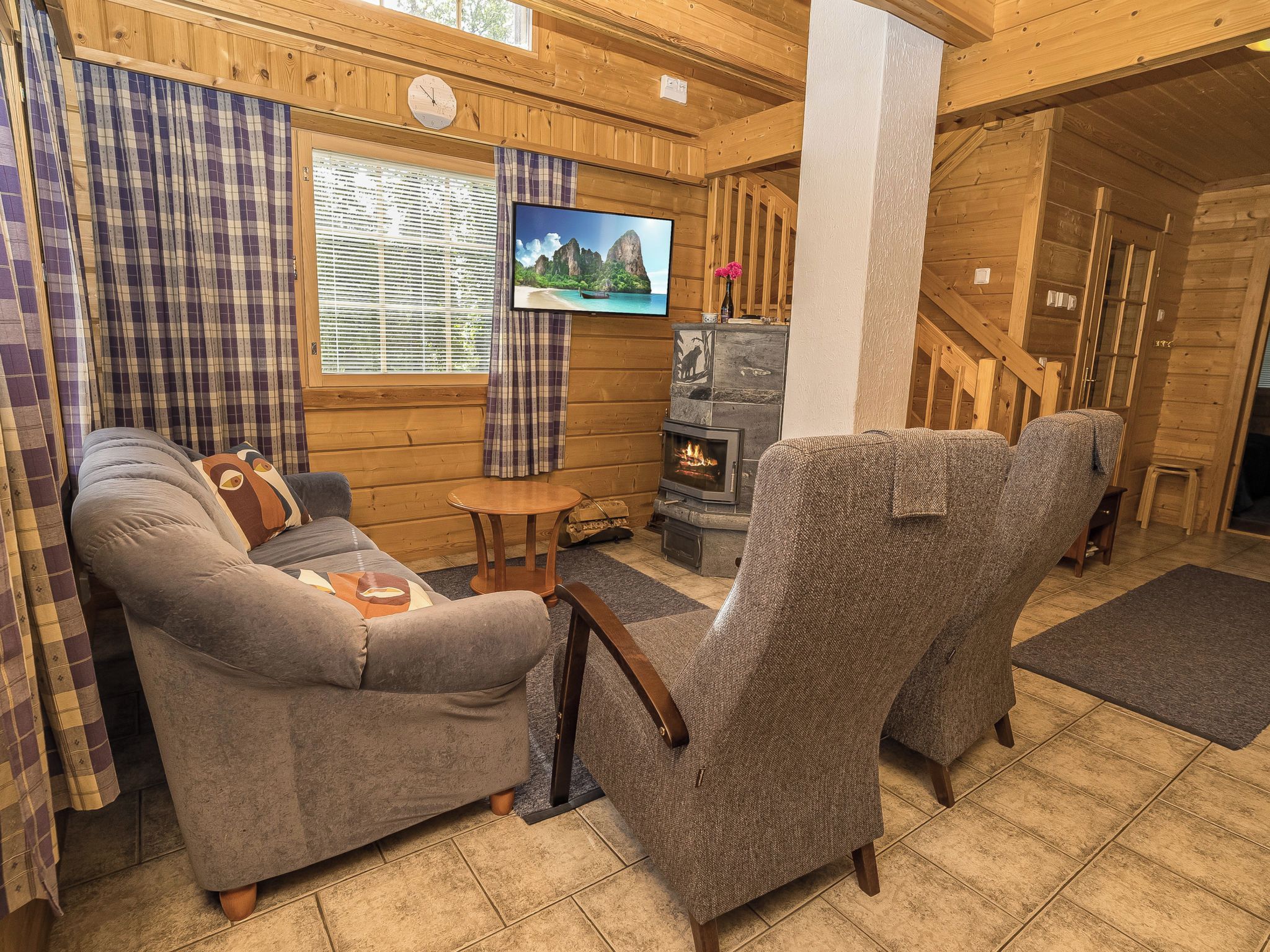 A cozy cabin interior with a sofa, armchair, and a fireplace.