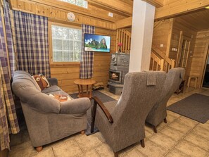 Un interior acogedor de cabaña con un sofá, un sillón y una chimenea.