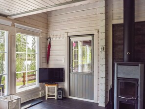 A room with a television on a small table, a door with a window, and a fireplace. - Lekojärven herra by Interhome (Äänekoski)