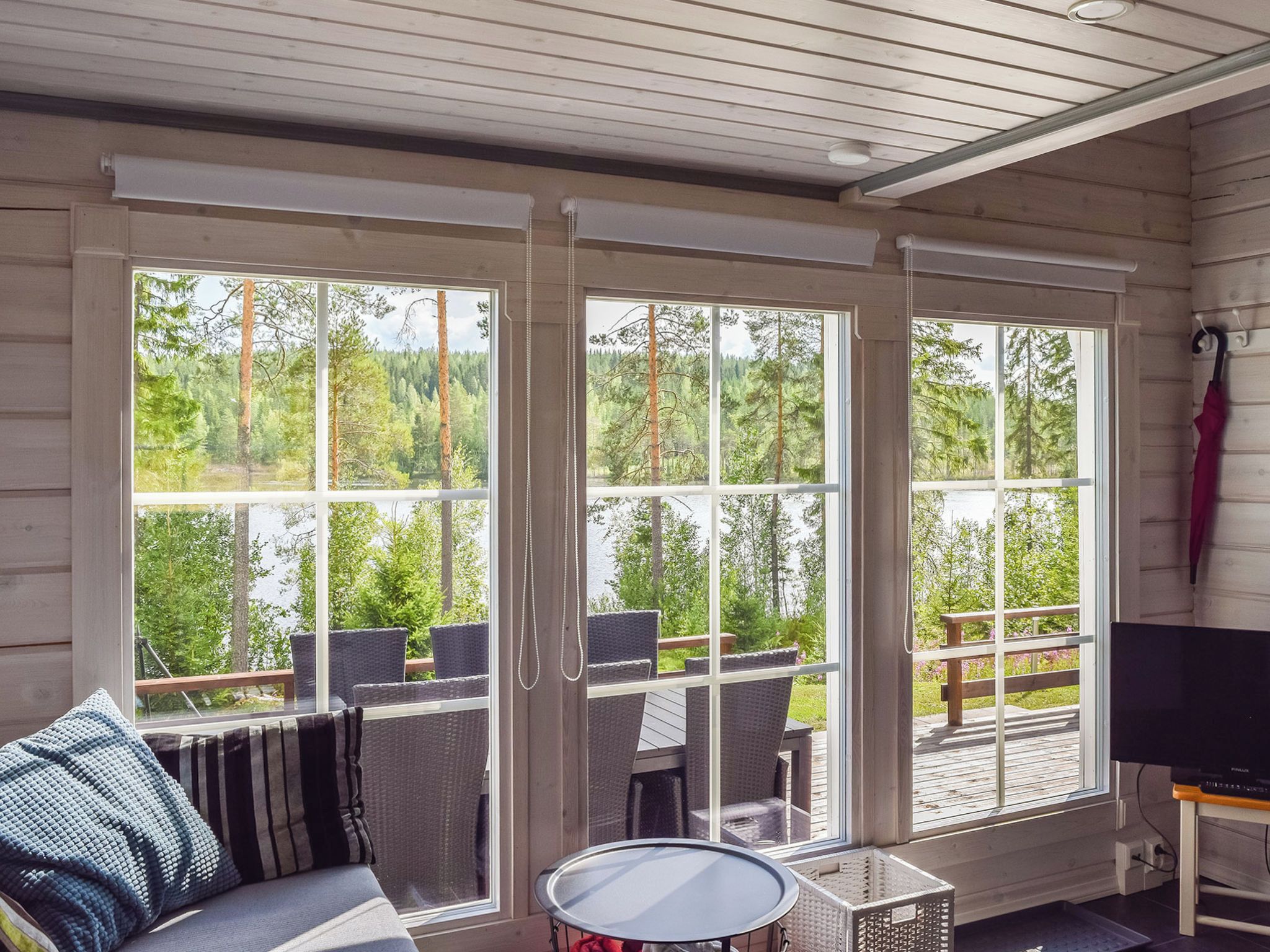 Ein Zimmer mit großem Fenster, einer Couch, einem Tisch und einem Fernseher.