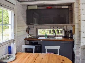 Cocina compacta con una mesa de madera, un lavamanos y un ventanal.