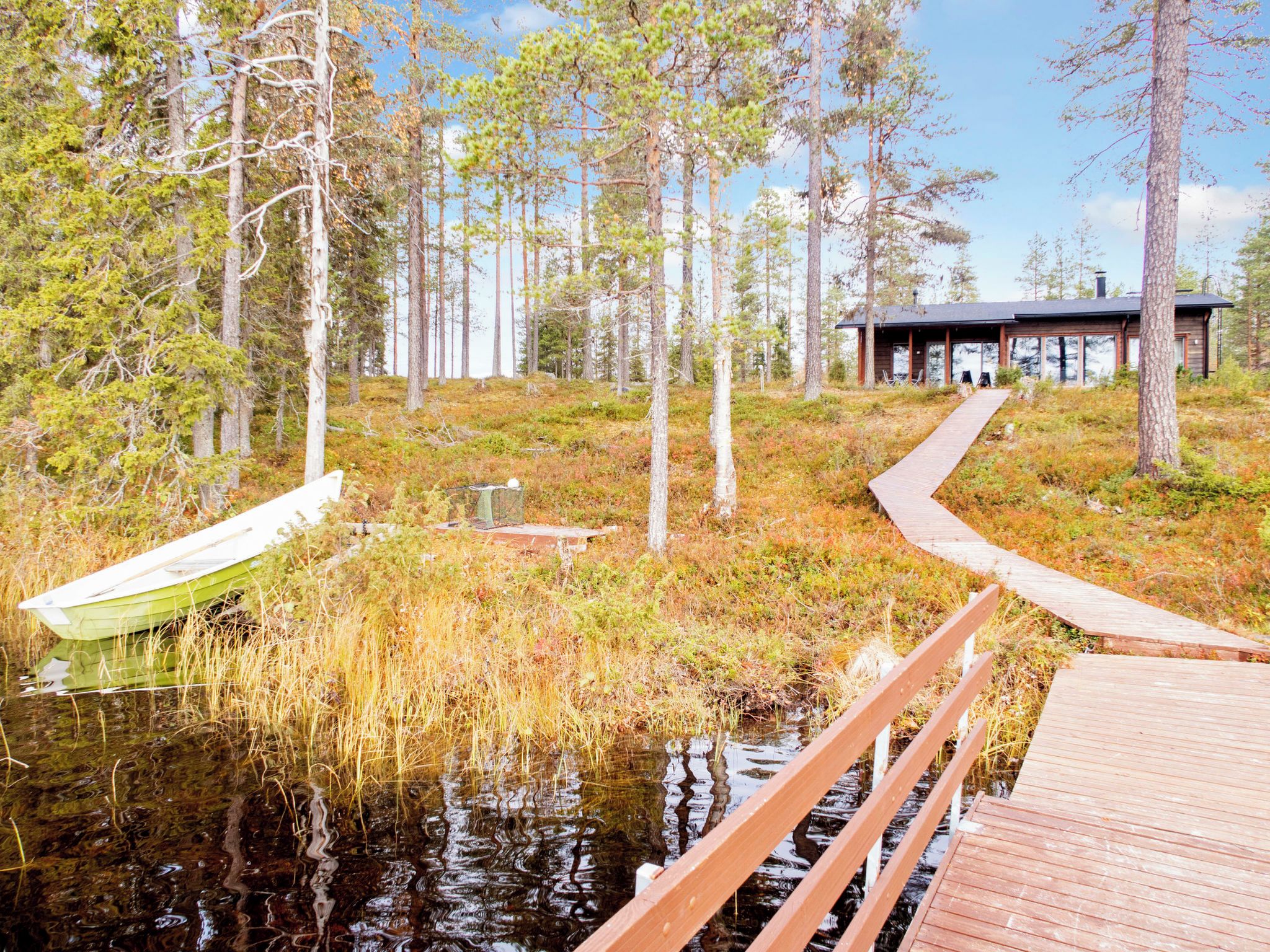 A wooden dock leading to a cabin surrounded by a forest.
