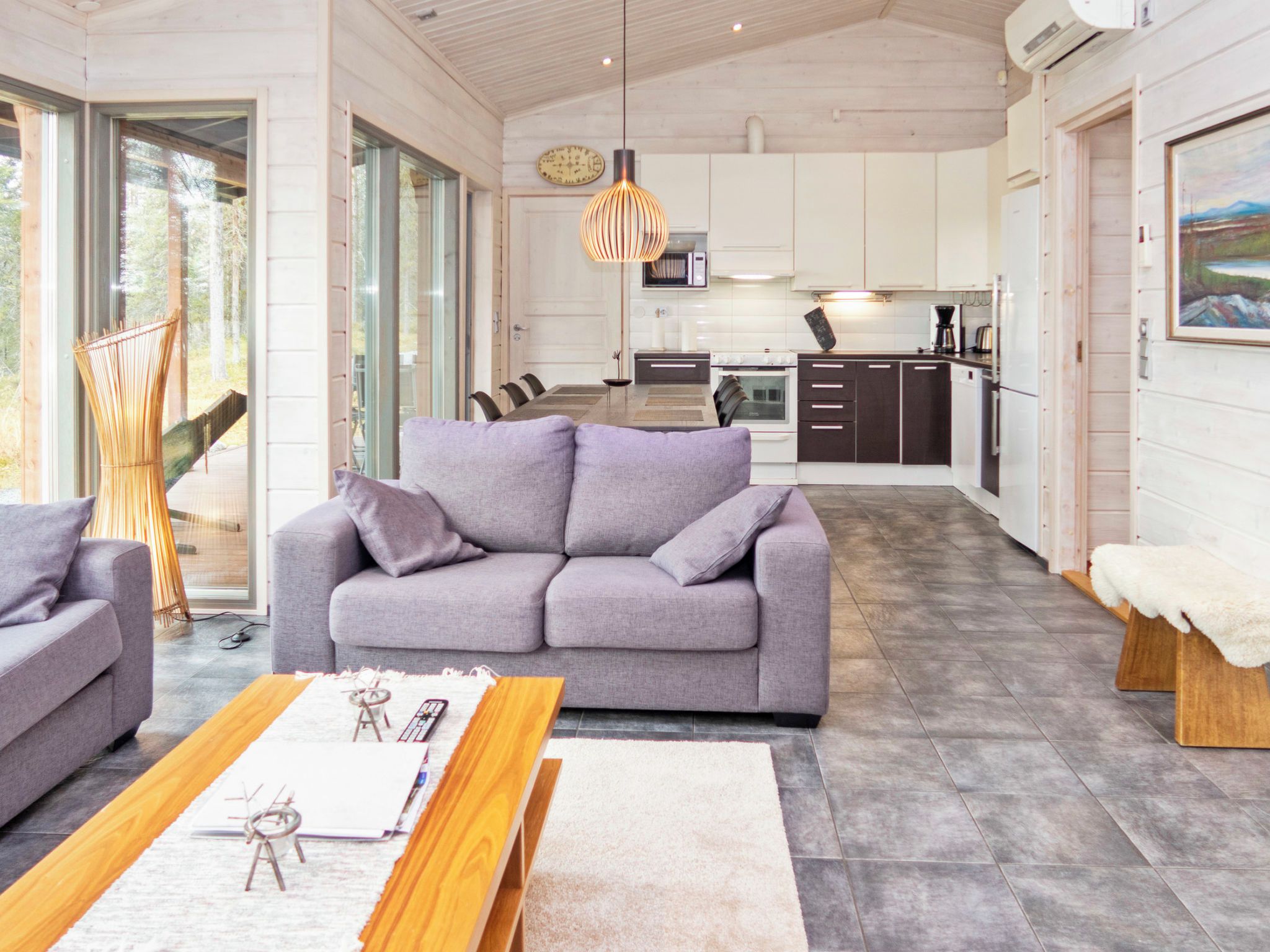A modern living room with a grey sofa, wooden coffee table, and a dining area with a table and chairs.