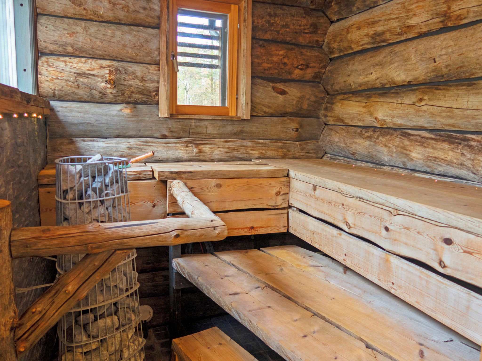 A cabin interior with a wooden bench seating area, a window, and a metal storage unit.