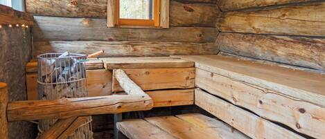 A cabin interior with a wooden bench seating area, a window, and a metal storage unit.