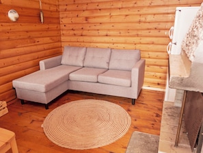 A cozy room with a grey sectional sofa, a woven rug, and a fireplace. - Lumikukka by Interhome (Kuusamo)
