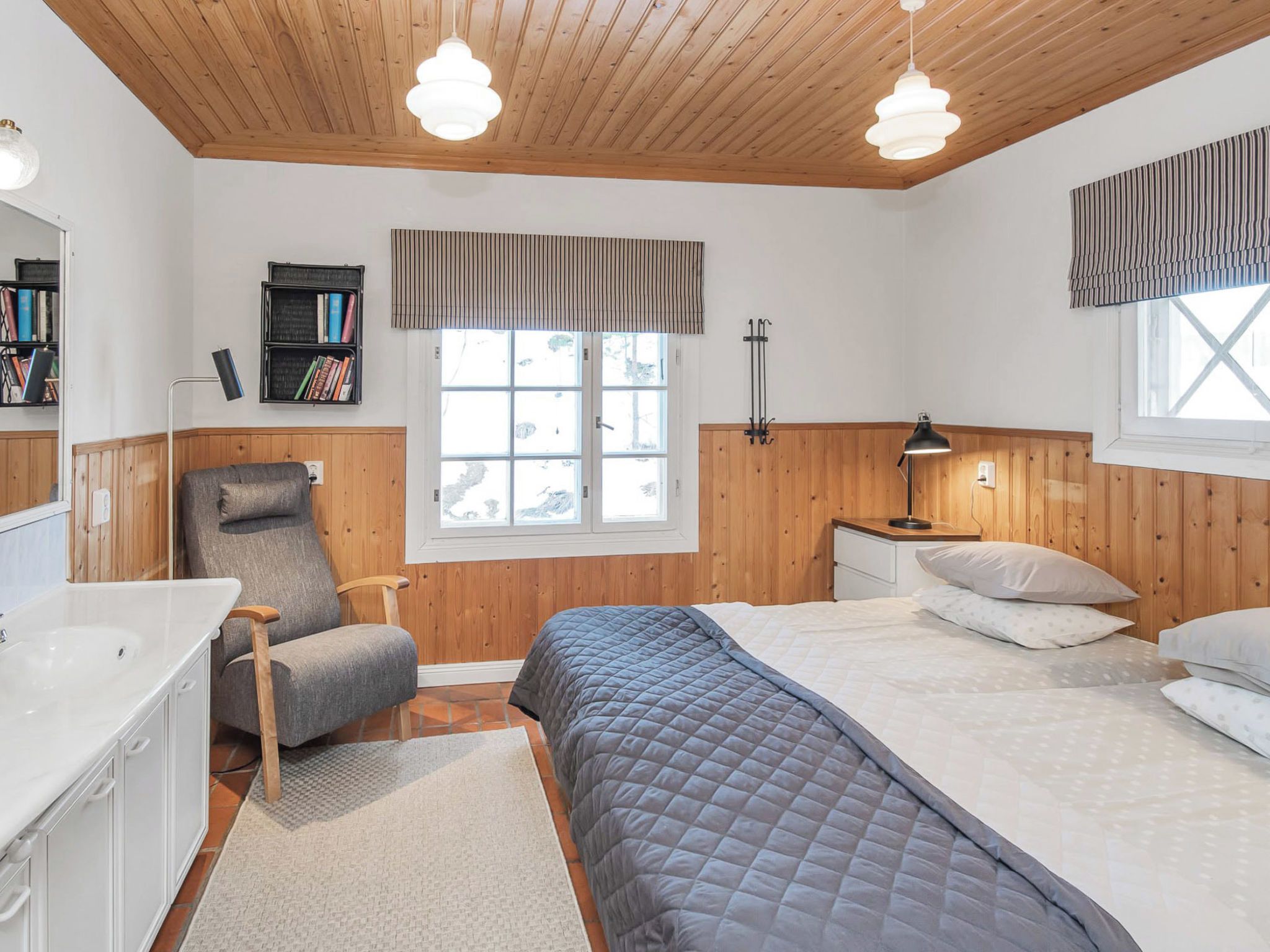 Une chambre à coucher comprenant un lit, des tables de chevet, une chaise, un bureau, une fenêtre et une bibliothèque.