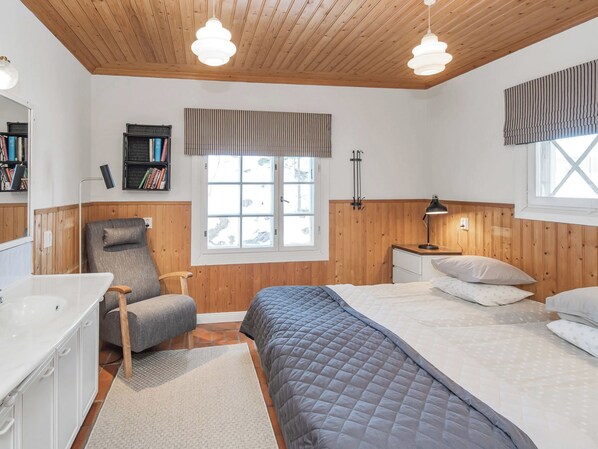 A bedroom with a bed, bedside tables, a chair, a desk, a window, and a bookshelf.