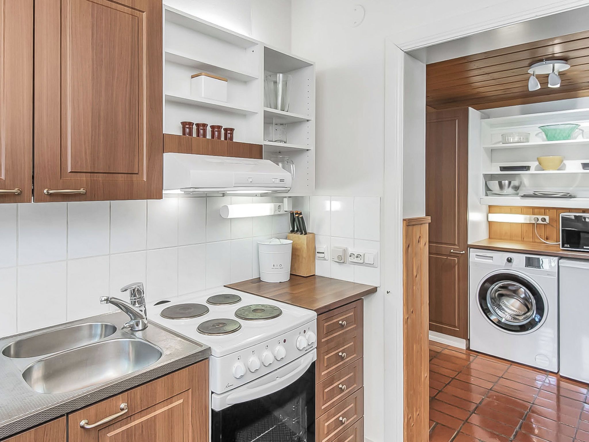 A compact kitchen with a stove, sink, and a built-in washing machine.