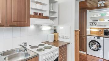 A compact kitchen with a stove, sink, and a built-in washing machine.