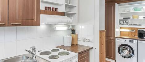 A compact kitchen with a stove, sink, and a built-in washing machine.