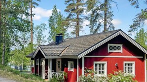 A red wooden cabin with a porch, a chimney, and a view of trees. - Satakieli by Interhome (Somero)