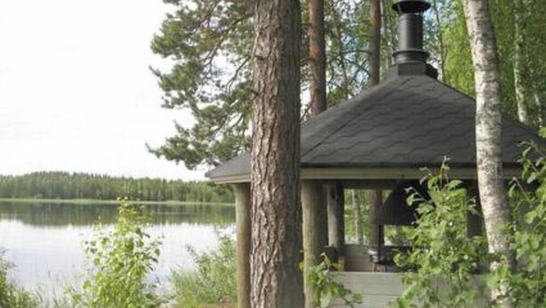 A gazebo with a chimney, surrounded by trees and a lake. - Varvali by Interhome (Konnevesi)