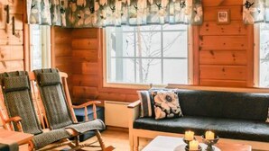 A cozy cabin interior with a rocking chair, sofa, and a table with candles. - Varvali by Interhome (Konnevesi)