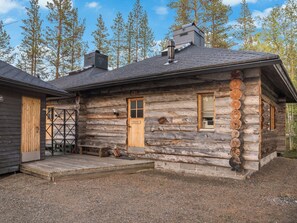 A log cabin with a wooden door, a window, and a chimney.