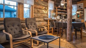 A cozy log cabin interior with a dining area, wooden chairs, a coffee table, and a kitchen with wooden cabinets. - Ylläsparit as. 2 by Interhome (Ylläsjärvi)