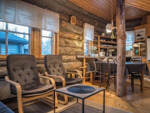 A cozy log cabin interior with a dining area, kitchen, and seating with a view of the outside. - Ylläsparit as. 2 by Interhome (Ylläsjärvi)