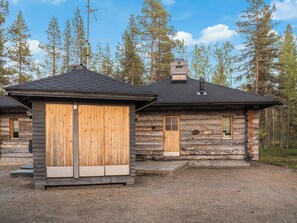 A log cabin with a wooden door and a chimney, surrounded by trees. - Ylläsparit as. 2 by Interhome (Ylläsjärvi)