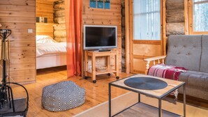 A cozy log cabin interior with a bed, a television on a wooden stand, a sofa, and a small table. - Ylläsparit as. 2 by Interhome (Ylläsjärvi)