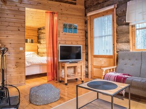 A cozy log cabin interior with a bed, a television on a wooden stand, a sofa, and a small table. - Ylläsparit as. 2 by Interhome (Ylläsjärvi)