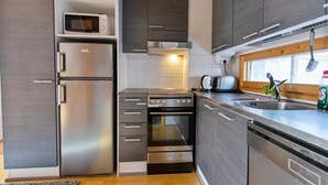 A modern kitchen with stainless steel appliances, wooden cabinets, and a window with a view.