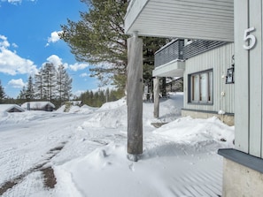 A snow-covered outdoor area with a building featuring a porch and a number '5' sign.
