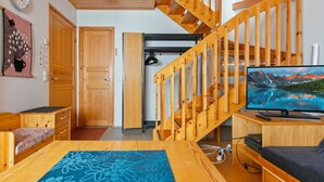 A wooden interior with a staircase, a television, and a bed.