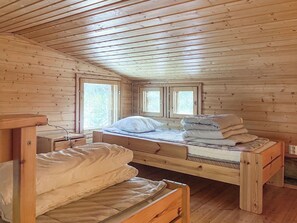Eine Holzhütte mit zwei Etagenbetten, einem kleinen Schreibtisch und einem Fenster, das natürliches Licht hereinlässt.