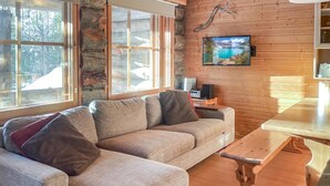 Ein gemütliches Wohnzimmer mit einer Eckcouch, einem Holztisch und einem an der Wand befestigten Fernseher.