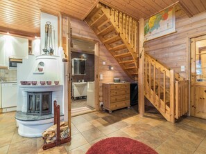 A wooden interior with a fireplace, a kitchen, a bathroom, and a staircase.