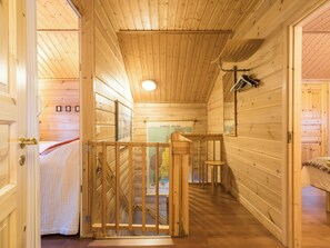 A wooden interior with a staircase leading to a loft area, a bed with a white bedspread, and a map on the wall.