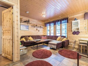 A cozy wooden interior with a sofa, a coffee table, and a dining area.